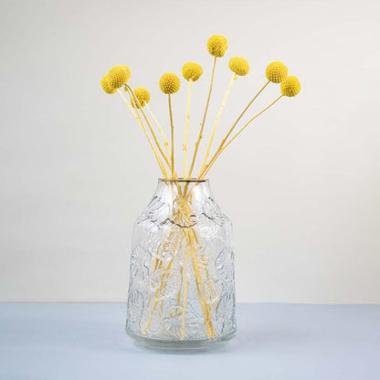 Clear glass vase with embossed design styled with yellow dried flower stems modern home decor accent for table.