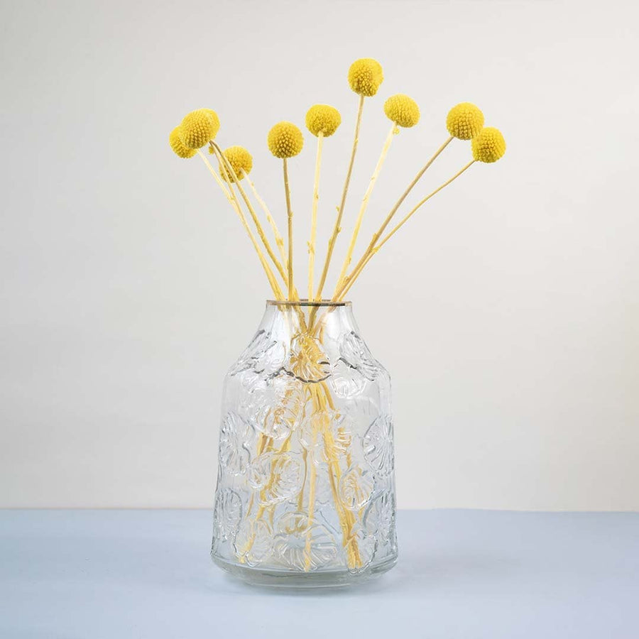Clear glass vase with embossed design styled with yellow dried flower stems modern home decor accent for table.
