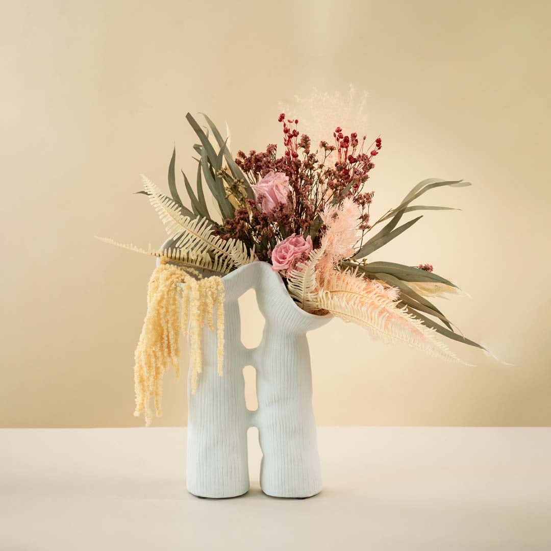 Modern white ceramic vase featuring fluid sculptural shape and minimalist ribbed texture for elegant interior styling.