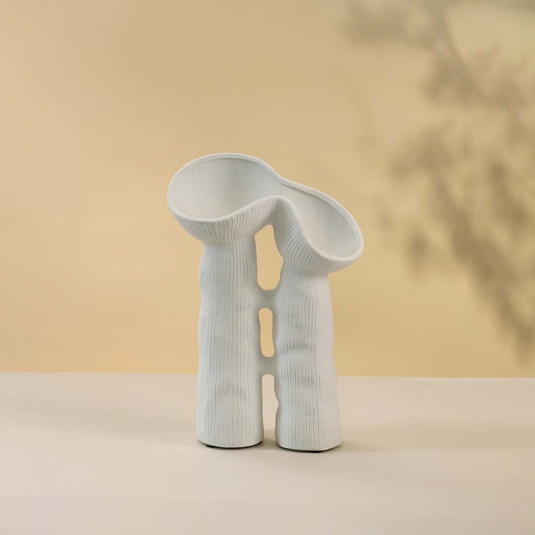 Modern minimalist white ceramic vase featuring creative sculptural curves and twin openings in matte finish against white background.