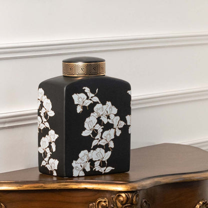 Black ceramic jar with white floral artwork placed on a wooden console offering a bold modern décor accent that enhances interior spaces with artistic style.