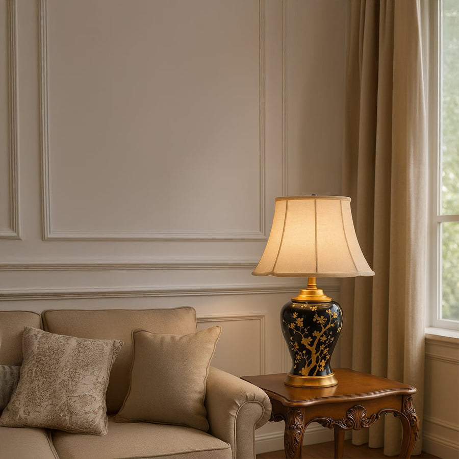 Elegant black and gold ceramic table lamp with beige shade placed on wooden side table illuminating a cozy beige sofa corner creating warm inviting ambiance.