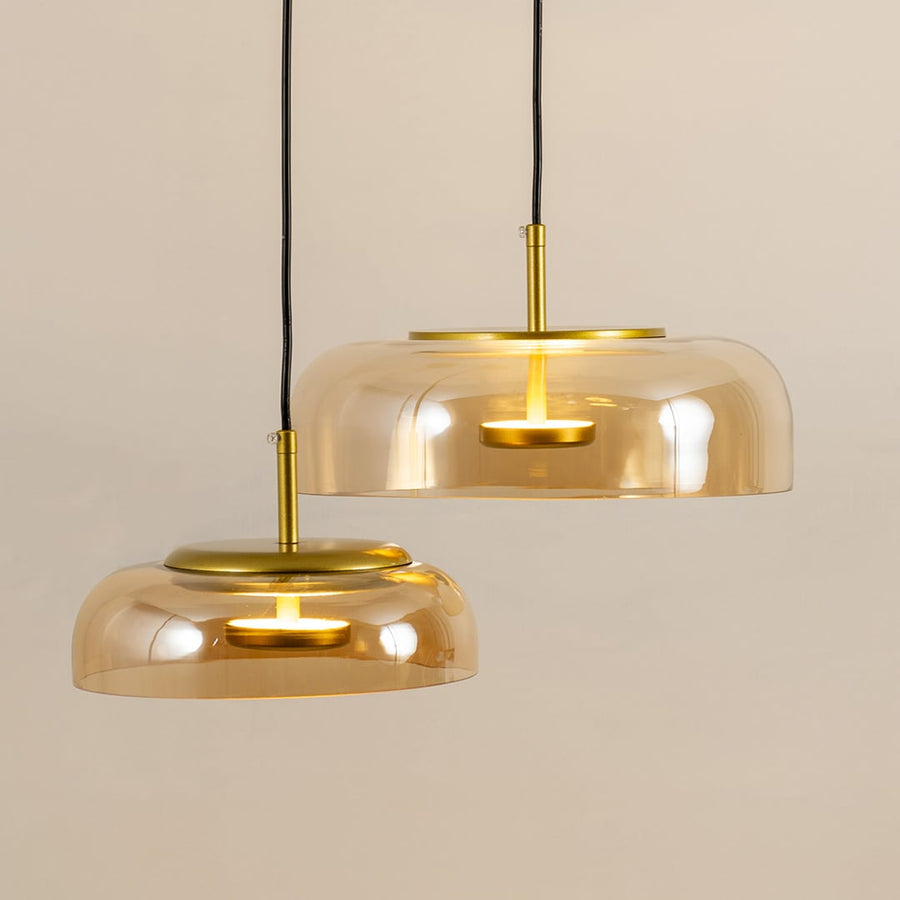 Amber glass pendant lights with gold metal fixtures illuminated to showcase luxury modern ceiling lighting elegance.