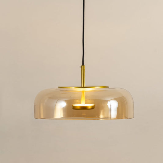Amber glass pendant light with gold metal fixture illuminated to display luxury decorative ceiling lighting elegance.