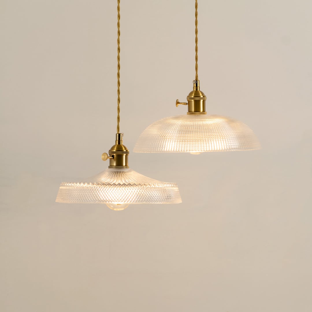 Clear ribbed glass pendant light with gold accents casting a warm glow for stylish interiors.