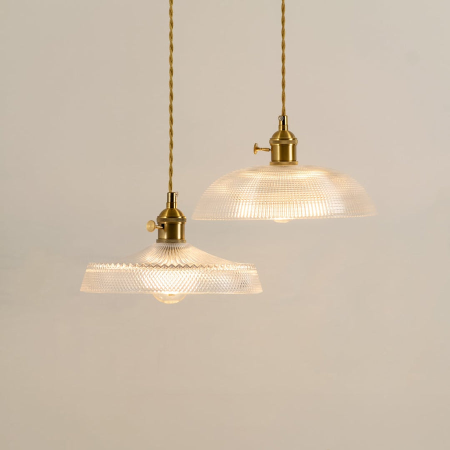 Clear ribbed glass pendant light with gold accents casting a warm glow for stylish interiors.