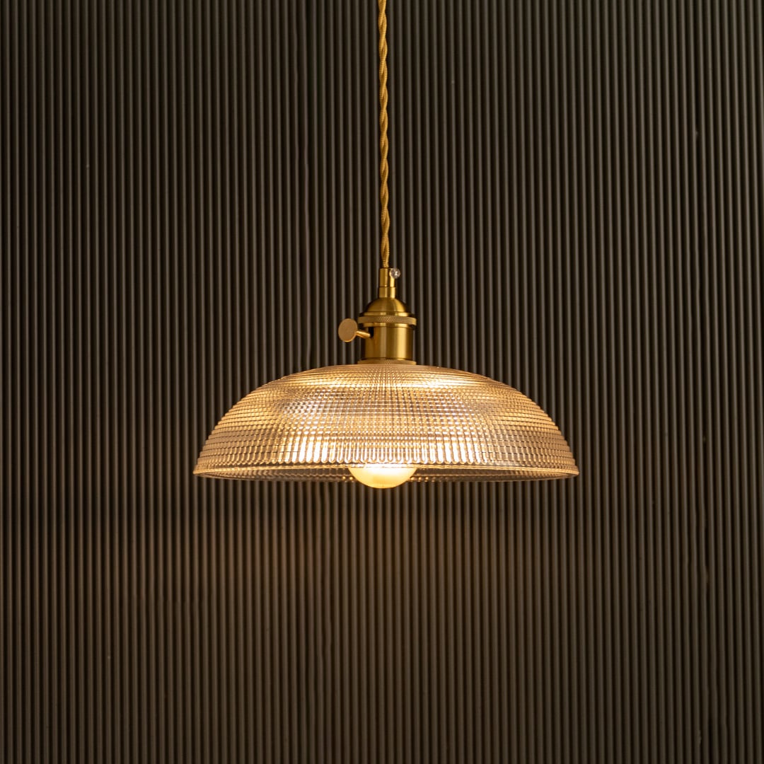 Vintage glass pendant light glowing beautifully against dark background highlighting glass texture.