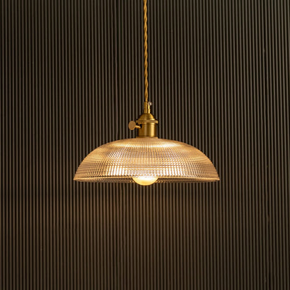Vintage glass pendant light glowing beautifully against dark background highlighting glass texture.