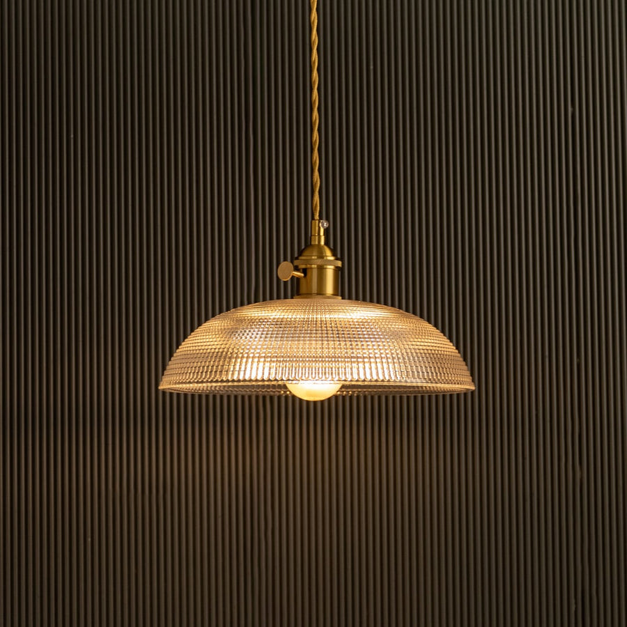 Vintage glass pendant light glowing beautifully against dark background highlighting glass texture.
