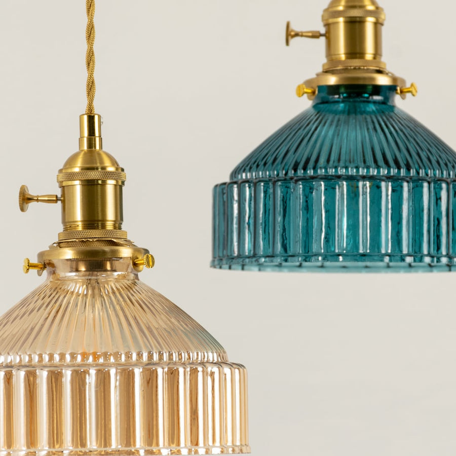 Gold metal pendant lights with blue and clear ribbed glass shades illuminated to display luxury ceiling lighting.