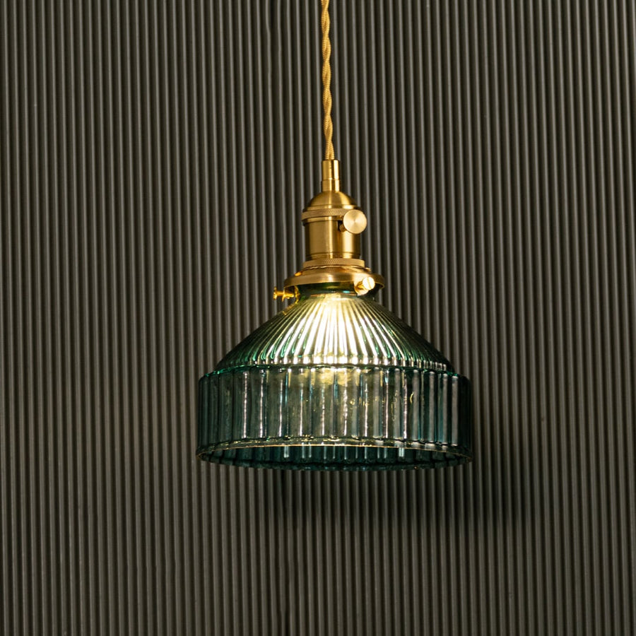 Blue ribbed glass pendant illuminated on dark background showcasing its rich color depth and metallic contrast for a stylish glow.