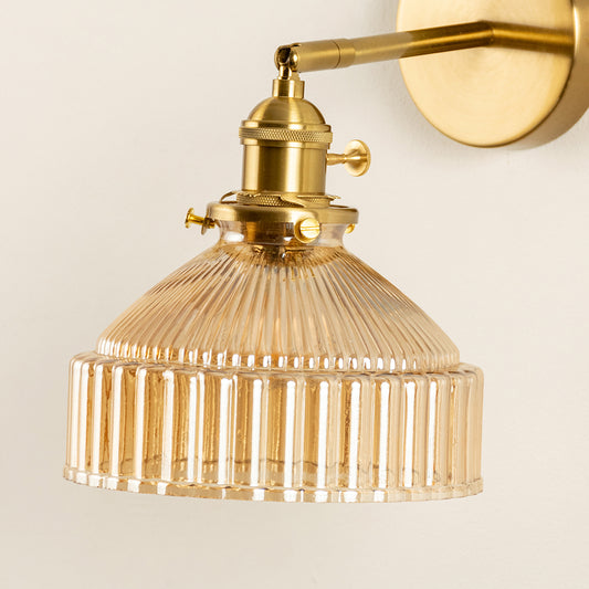 Closeup of gold metal wall light with ribbed glass shade showcasing detailed texture and premium finish for modern interior decor styling.