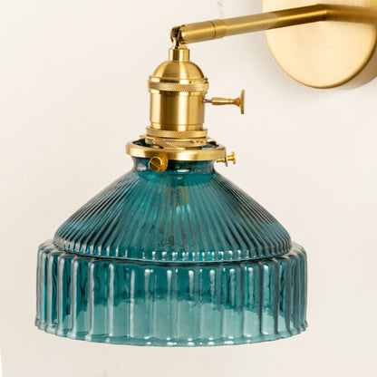 Closeup of gold metal wall light with blue ribbed glass shade showcasing detailed texture and premium finish for modern decor styling.