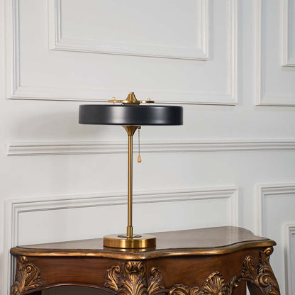 Contemporary black and gold round shade table lamp displayed turned off against white background for modern interiors.