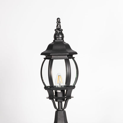 Closeup of decorative tall outdoor black pillar lamp with curved round glass panels and LED bulb showing vintage style.