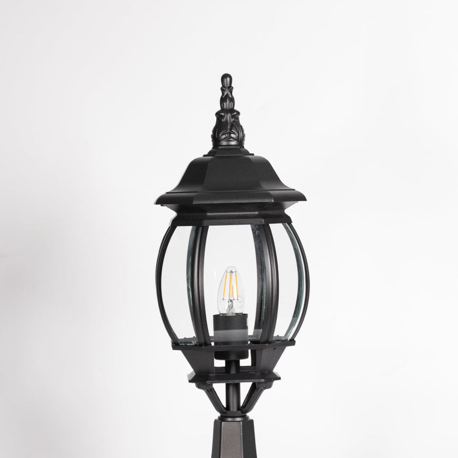 Closeup of decorative outdoor black pillar light with clear curved glass and LED bulb highlighting premium classic design.