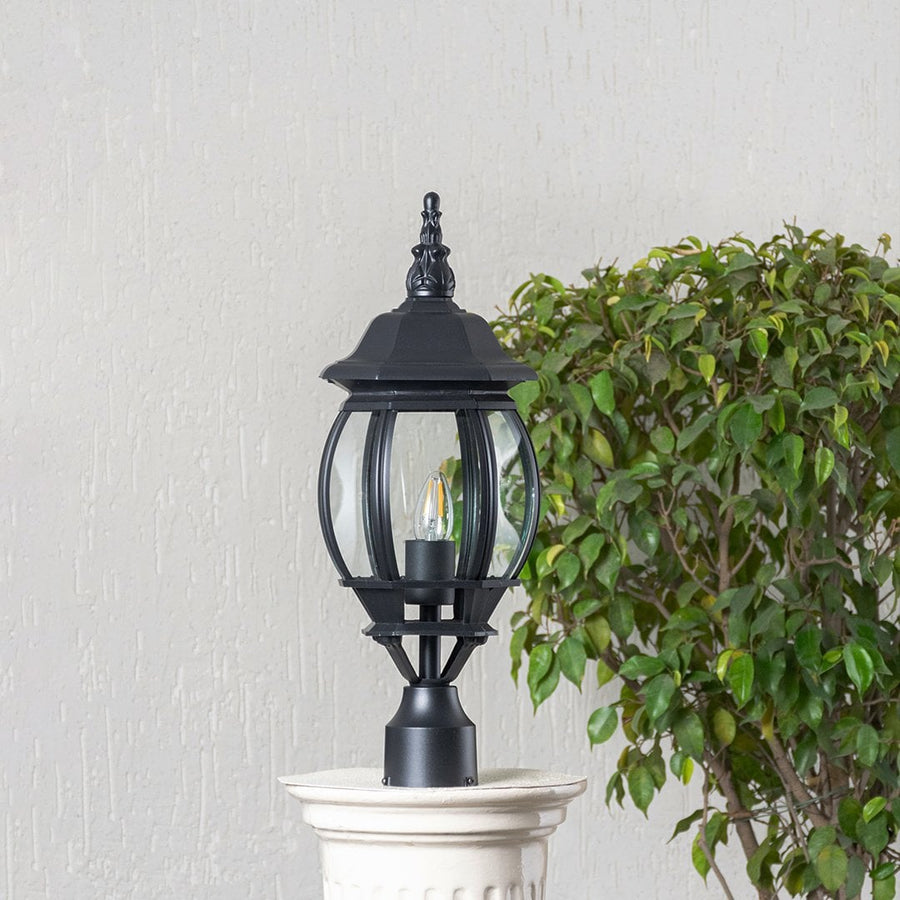 Classic black outdoor pillar lamp with clear curved glass shade placed on stone pillar ideal for entrance and garden.