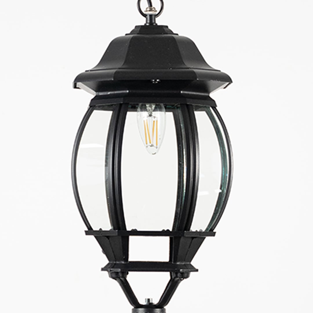 Closeup of outdoor hanging lantern light showing bulb reflection and detailed glass pattern.
