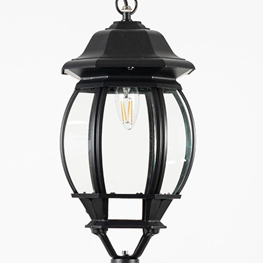 Closeup of outdoor hanging lantern light showing bulb reflection and detailed glass pattern.
