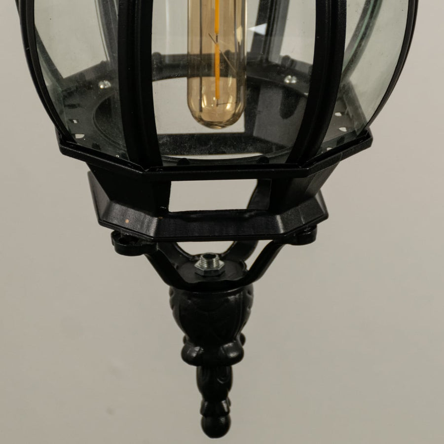 Detailed closeup of hanging lantern light focusing on curved glass and metallic black design.