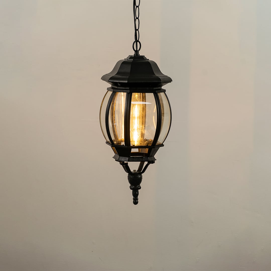 Hanging outdoor lantern light glowing softly on white background with classic round shape and black finish.
