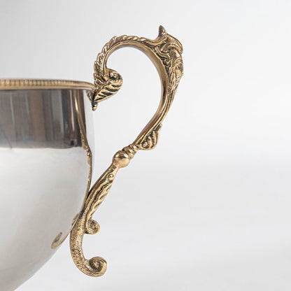 Round silver metal bowl with reflective interior and gold handles shown from top on a clean white background.