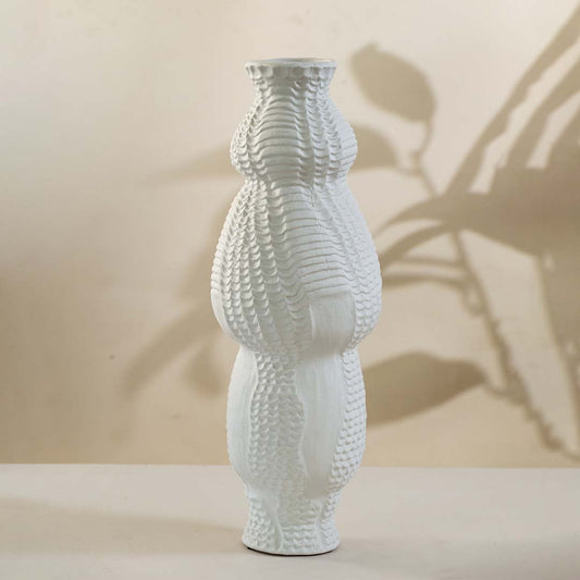 Handcrafted tall white ceramic vase with sculptural curves shown on white background perfect for modern interior decoration.