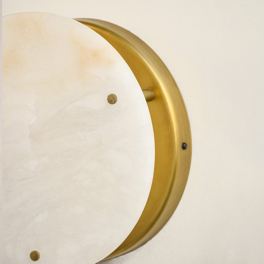 Detailed view of circular marble wall sconce showing natural stone veining and sleek metallic edges crafted for elegant home lighting.