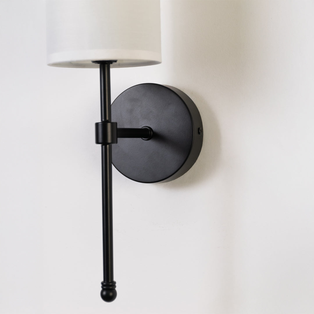 Minimal wall light in black metal finish with fabric shade for bedroom or living room decor lighting white background.