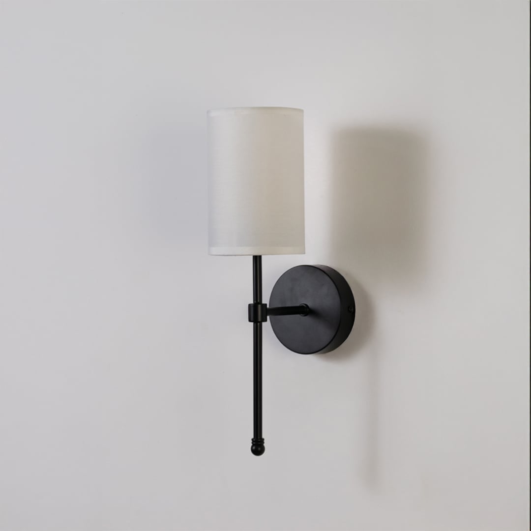 Black metal wall light with white fabric shade on a clean white background with light off highlighting its sleek modern design.