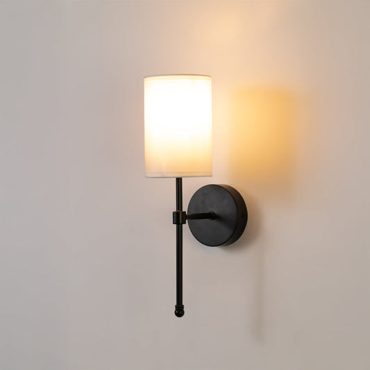 Black metal wall light with white fabric shade glowing softly on a white background perfect for bedroom hallway or living room lighting.