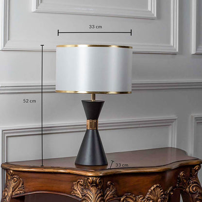 Black ceramic table lamp with fabric shade and brass detailing shown with 52cm height and 33cm width.