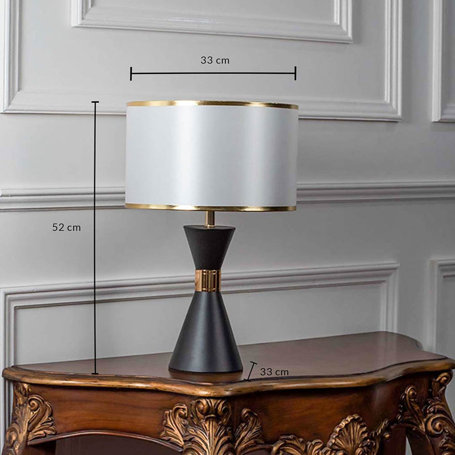 Black ceramic table lamp with fabric shade and brass detailing shown with 52cm height and 33cm width.