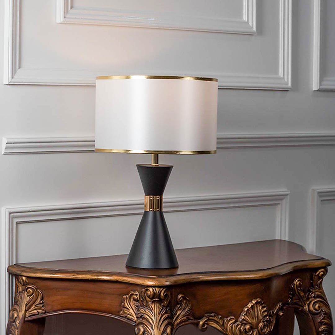 Modern table lamp with black tapered base and white fabric shade on wooden table stylish lighting for bedroom and living room decor.