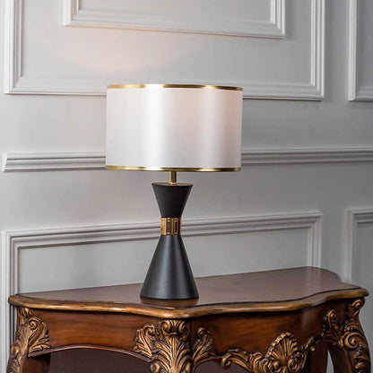 Modern table lamp with black tapered base and white fabric shade on wooden table stylish lighting for bedroom and living room decor.