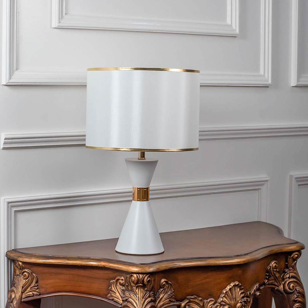 White ceramic table lamp turned off with drum shade and golden accents displayed on plain white background.