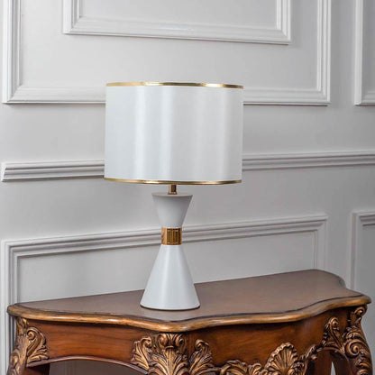 White ceramic table lamp turned off with drum shade and golden accents displayed on plain white background.