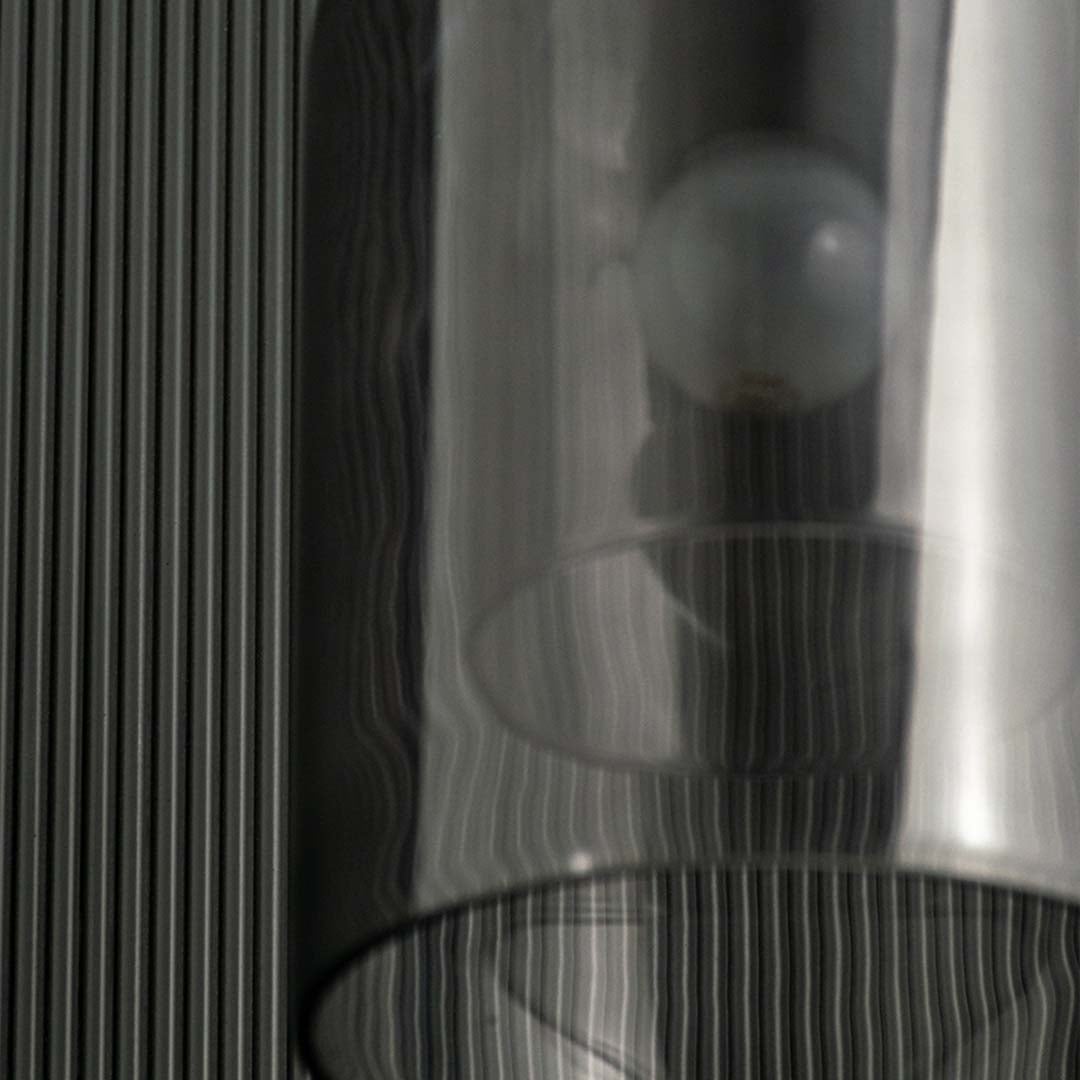 A closeup of the smoked glass dome pendant light highlighting its glowing filament bulb and smooth curved glass design for elegant interior lighting.