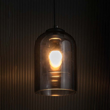 A smoked glass dome pendant light glowing warmly against a dark textured backdrop creating a rich ambient lighting effect for contemporary home styling.