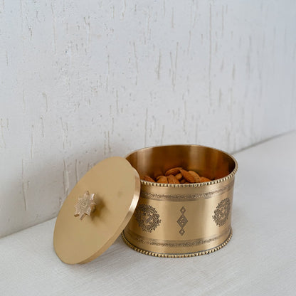 Gold metal storage jar with engraved design presented inside a black gift box with lid open for packaging display.
