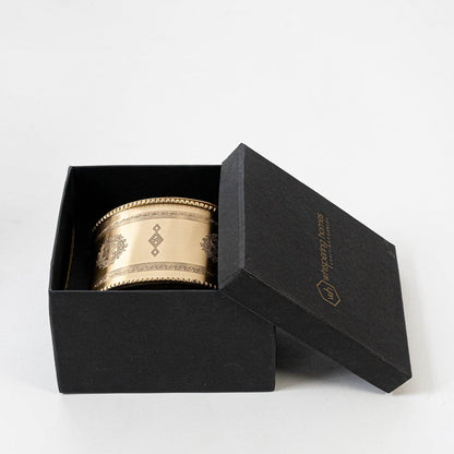 Gold round metal storage jar with decorative engraved pattern and closed lid shown on plain white background front view.