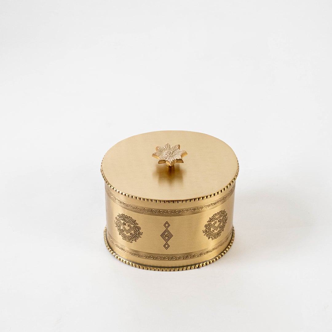 Gold metal round storage jar with engraved details shown on white background with measurements 13 cm by 11.5 cm.