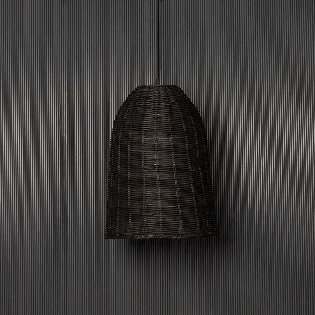 Black rattan pendant light on black background highlighting its artisanal weave and natural contours.