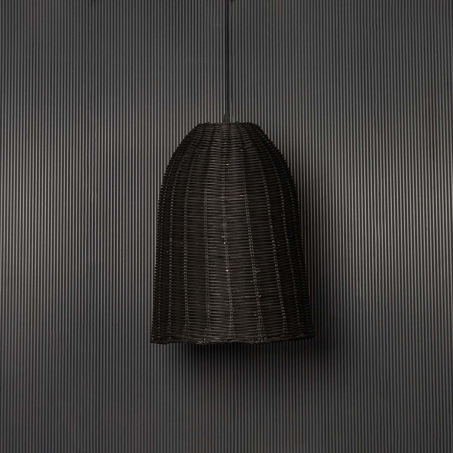 Black rattan pendant light on black background highlighting its artisanal weave and natural contours.