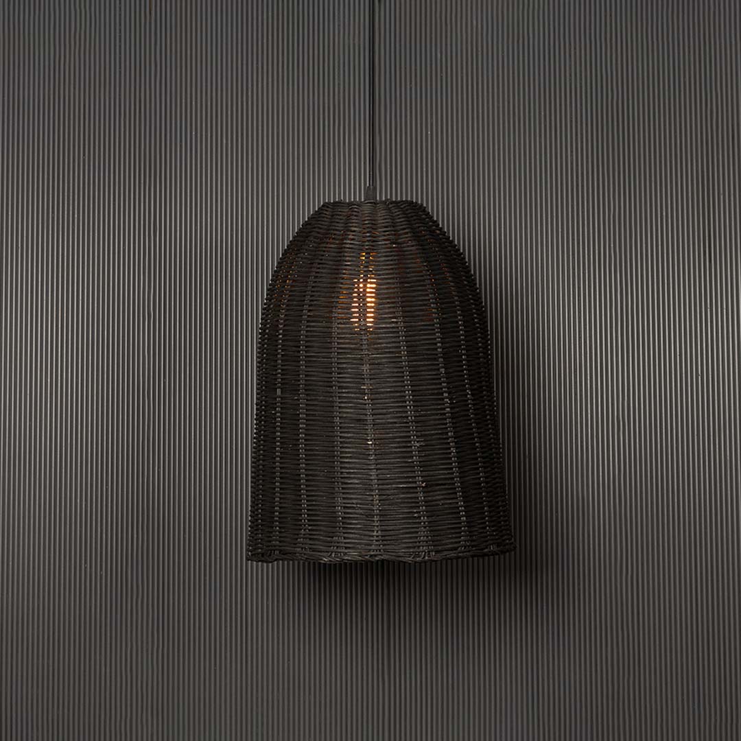 Black rattan pendant light glowing warmly against a dark background adding modern organic elegance.