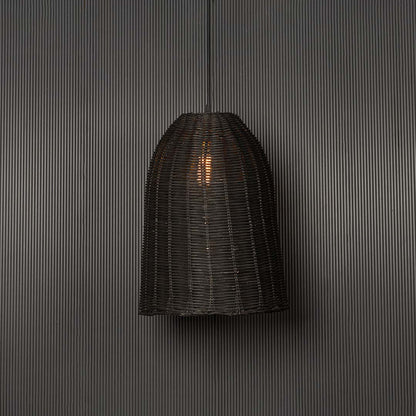 Black rattan pendant light glowing warmly against a dark background adding modern organic elegance.