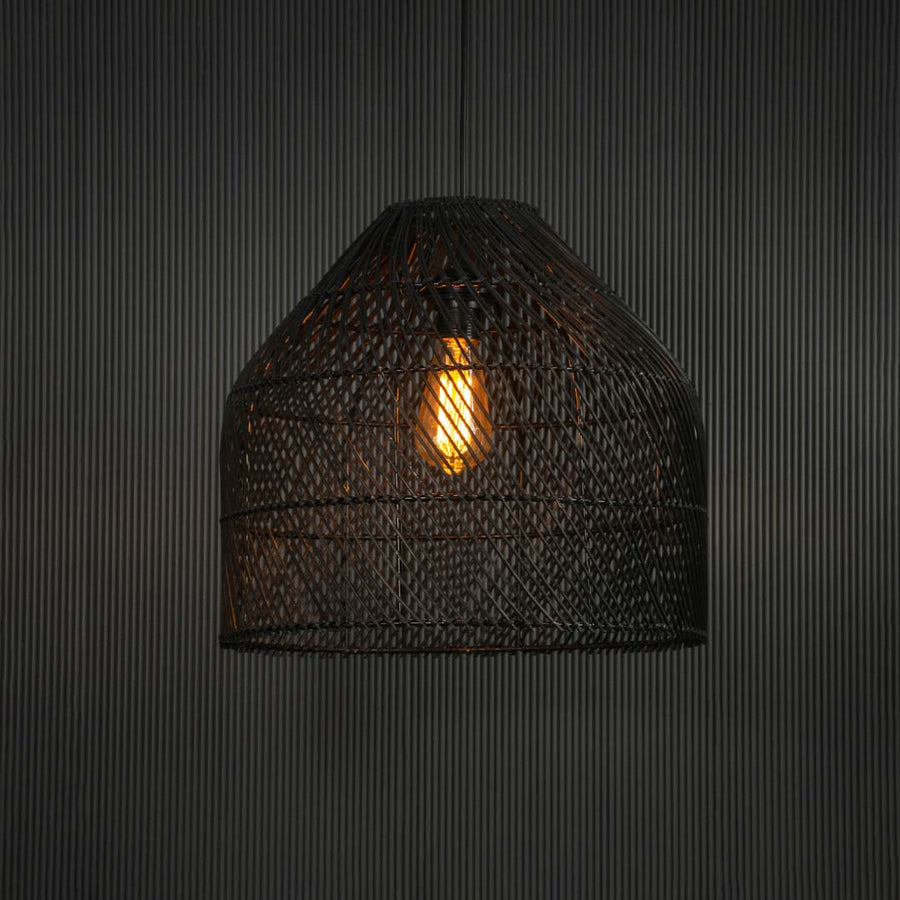 Black rattan pendant light glowing warmly against dark background creating cozy atmosphere with soft elegant lighting.