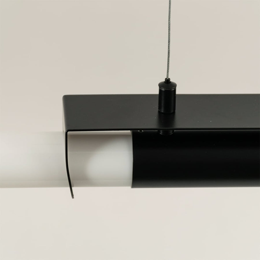 Closeup of black metal pendant light showing sleek frame and white acrylic tube for modern ceiling decor focus.
