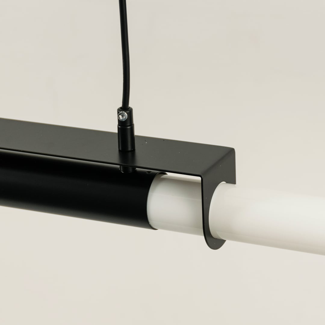 Detailed closeup of black pendant light showing metal frame and smooth white light bar for contemporary decor focus.
