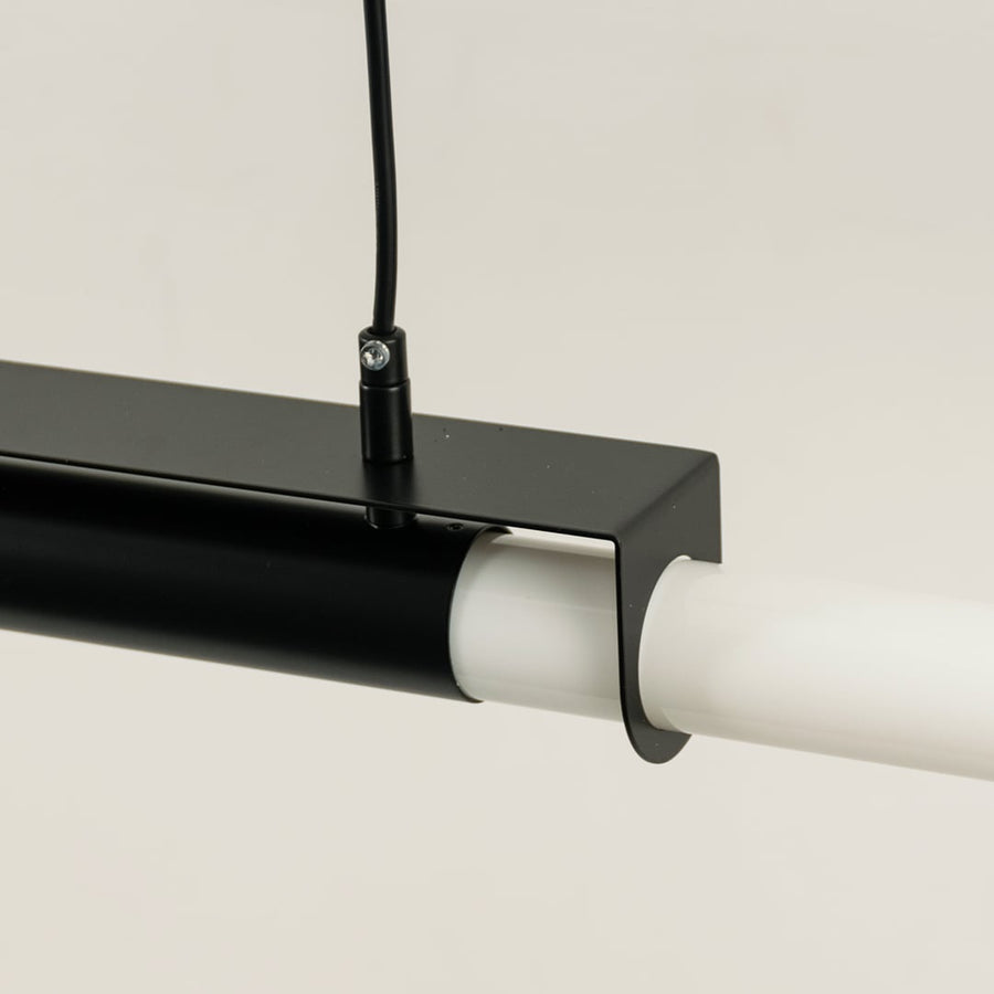 Detailed closeup of black pendant light showing metal frame and smooth white light bar for contemporary decor focus.